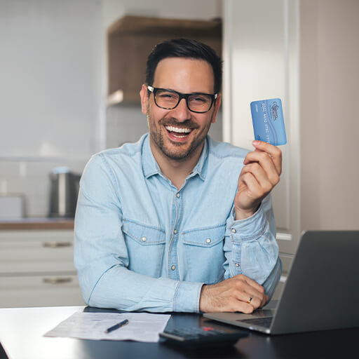 Man with Community First Credit Union Visa card and laptop